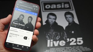 Un fan usa un teléfono para acceder a un sitio web de venta de entradas en línea para comprar boletos para la gira "Live '25" de Oasis el 31 de agosto de 2024. Crédito: Foto de OLI SCARFF/AFP vía Getty Images